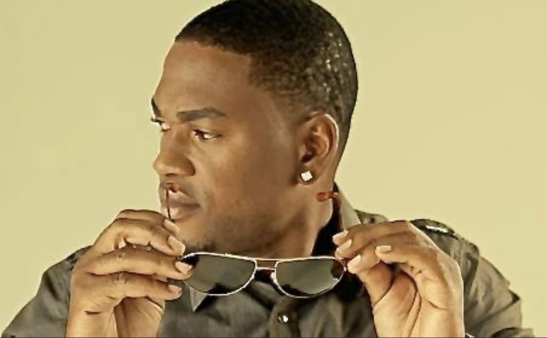 A man holding his sunglasses up to the side of him.